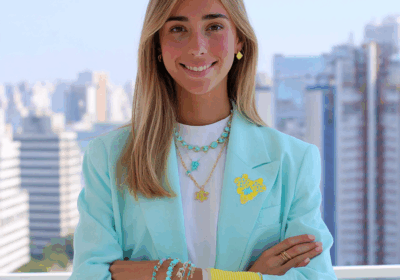 Four women in stylish pastel outfits in an office setting, with cityscape views in the background.