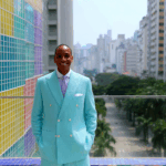 Men in colorful suits with city views, showcasing modern style against an urban backdrop.