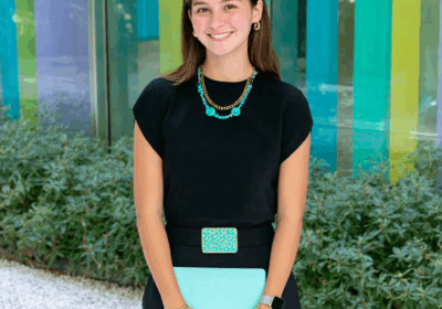 Women in stylish outfits holding colorful folders, standing outside modern, vibrant architectural buildings.
